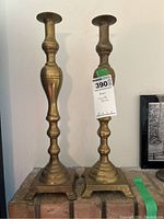 Front view of the pair of brass candlesticks showing height and square bases.