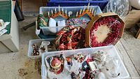 Overview of stored Christmas decorations including wreaths, village miniatures, and stockings in plastic bins