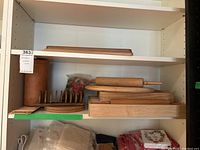 Shelf holding multiple wooden kitchen items including cutting boards, rolling pins, a wine cooler, and others.