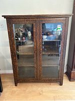 Front view of the wood display cabinet showing double glass doors and interior shelves.