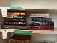 Books stacked on shelves showing titles such as World of Ice and Fire, The Dragon Heir, Iron & Rust, Wars of the Roses, The Outlandish Companion volumes