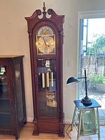 Full frontal view of the clock showing entire wooden case and glass door