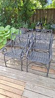 Four wrought iron patio chairs arranged on a wooden deck, showing front and side views.