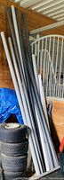 Ten PVC pipes, grey and black, leaning against wall, lengths up to 10 feet, condition fair to good