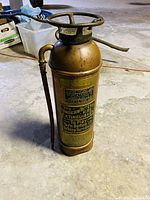 Front view showing brass and copper antique fire extinguisher with detailed patent and test labels.