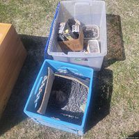 Two large plastic crates containing assorted nails and ramset shot boxes outdoors on grass.