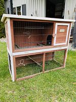 Front view of rabbit cage showing two levels, wire mesh front, and wooden door with latch.