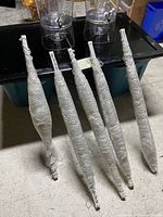 Five sets of beaded curtains, each wrapped in bubble wrap, leaning against a surface.