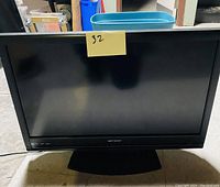 Front view of Emerson 32-inch LED TV showing screen and stand with a sticky note labeled '32'.