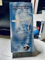 Side view of the box showing product specifications including 5 inch 3-diopter glass lens, LED count, adjustable arm length, dust cover, and clamp mount.