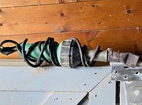 Full body view of the Leister Triac S hot air blower lying horizontally, cord coiled around the handle and nozzle visible.