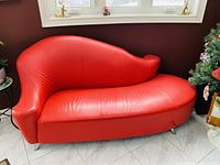 Full front view of red leather love seat showing curved design and armrest shape.