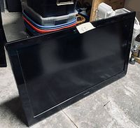 Samsung 52 inch plasma TV leaning against a wall on a concrete floor, no stand attached.