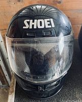 Front view of Shoei black full-face motorcycle helmet with clear visor and Shoei logo on forehead area.
