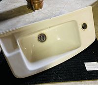 Top view of the rectangular white ceramic sink showing the flat edges, drain grate with multiple holes, and single faucet hole on the right side.