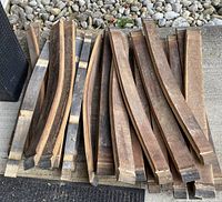 Top view of a stack of oak wine barrel slats showing natural wood grain and curved shape