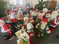 Full group of 16 Annalee dolls including snowmen, Santas, Mrs. Claus, polar bear and child doll, displayed on a table.