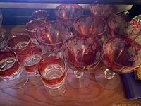 Side view showing both sets of ruby red goblets including 6 Kings Crown thumbprint goblets and 7 Bryce cranberry water goblets with grape design