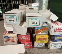 Stack of sealed set boxes including Fleer 1990 Basketball, Fleer 1990 Baseball, Donruss 1990 Puzzle and Score baseball set