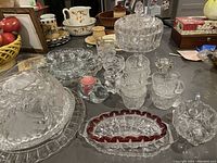 Clear glass covered dessert dish, pedestal candy dish, ruby red gold relish dish, small mini punch or demitasse cups, and clear glass platters.