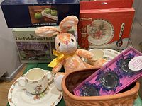 Overview of lot items showing Bunnykins dishware, plush bunny, fairy house box, apple candles, and candle holders.