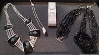 Overview of all items in the lot including Suzanne Somers rhinestone watch, black beaded bracelet, and several black and silver-tone necklaces