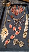 Jewelry lot with necklaces, bracelets, earrings, ring, and watch displayed in a black velvet tray.