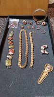 Full collection of gold-tone jewelry items with ruby and rhinestone accents on a black tray