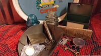 Photo showing Maxwell House coffee tray with other small vintage items including hanging food scale, insulators, keys, tins, and a pocket watch.