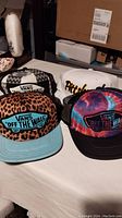 Four hats including three Vans 'Off The Wall' hats: black and white checkered, leopard print with blue brim, tie-dye multicolor, and one white Pittsburgh Steelers hat with black mesh back.