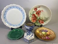 Wide shot of all items including porcelain plates and ceramic jar, various styles and colors