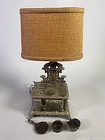 Front view of cast iron dollhouse stove lamp with miniature pots and pans in front