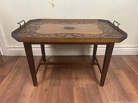 Full view of the wooden tray top table showing carved details and metal handles on sides