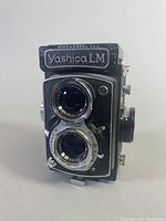 Front view showing Yashica LM branding and dual Yashinon lenses with aperture and focus rings.