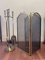 Full view showing the brass fireplace tool set with stand and the brass fireplace screen side by side
