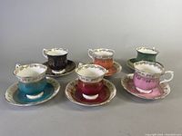 Group photo of all six teacup and saucer sets showing different colors and gold detailing.