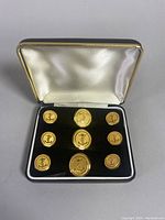Set of nine gold-toned WW2 military navy jacket buttons displayed in original box with velvet interior.