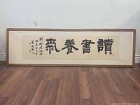 Full view of framed Asian calligraphy featuring four large Chinese characters and additional smaller script on the left side.