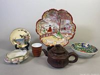 Full view of all items from front angle showing entire lot including the porcelain bowls, teapot, sake cups, plate, and dish.