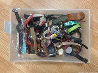 Plastic bin containing about 12 vintage watches with various bands and dial styles.