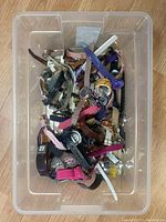 Clear bin containing numerous assorted wristwatches of different styles, colors and conditions piled together.