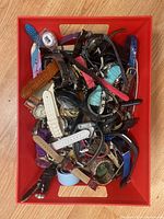 Photo of red bin filled with assorted wristwatches with various types of bands and watch faces