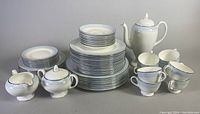 Full set displayed showing coffee pot, sugar bowl, creamer, stacked plates, cups and saucers arranged in groups