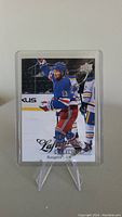 Front image of Alexis Lafreniere rookie hockey card in protective sleeve showing player in action for New York Rangers.