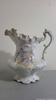Full side view of the antique floral porcelain jug with gold accents and ornate handle