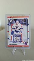 Front of Curtis Joseph rookie hockey card showing the player in goalie pose in St. Louis Blues uniform, rookie card text and Score logo.