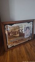 Front view of the extra large vintage Coca-Cola bar mirror with wooden frame showing the design and image of a woman.