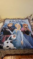 Full view of the tapestry blanket on a bed showing Frozen characters and logo.
