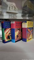Three Harry Potter hardcover books displayed upright, showing colorful front covers and spines.