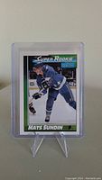 Front view of Mats Sundin rookie hockey card in plastic sleeve on stand.